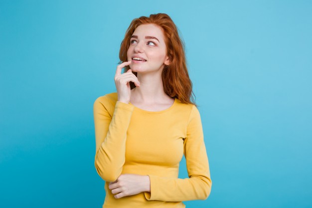 portrait-of-happy-ginger-red-hair-girl-with-freckles-smiling-looking-at-camera-pastel-blue-background-copy-space_1258-782